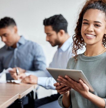Colaboradora sorrindo com tablet ao lado de colegas